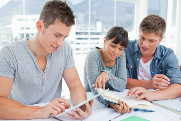 Un grupo de estudiantes que trabajan como uno utiliza una tableta y los demás — Foto de Stock