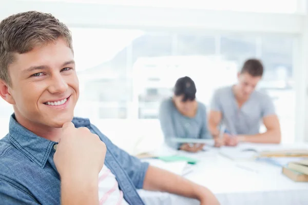 A smiling student with his hand near his chest as he looks into — Stock Photo, Image