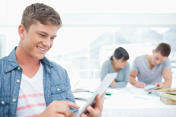 Усміхнений чоловік використовує планшетний ПК перед друзями — стокове фото
