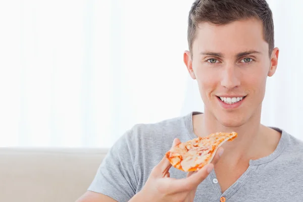 Bir adam bir dilim pizza tutar olarak oturan — Stok fotoğraf