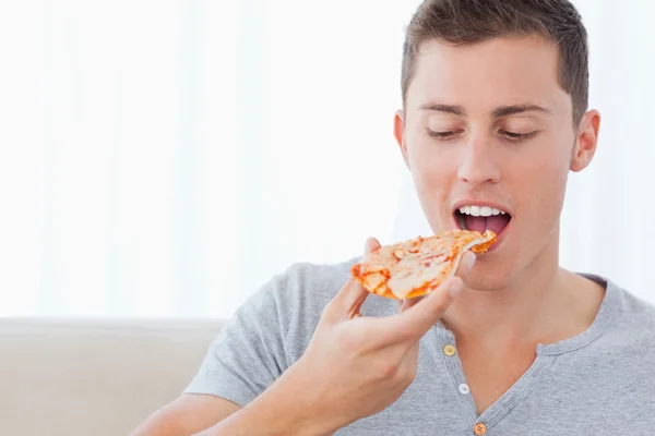Een man kijken naar de plak van pizza die hij is ongeveer om te eten — Stockfoto