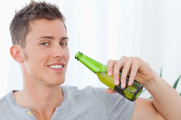 Een lachende man met bier in de buurt van zijn mond — Stockfoto