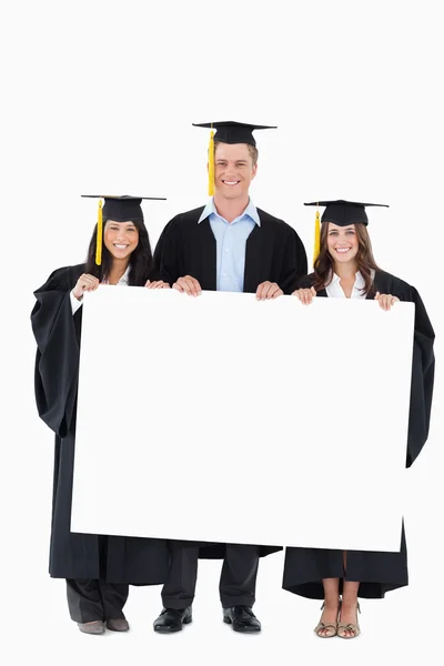 Volledige lengte van drie afgestudeerden van college houden sommige lege p — Stockfoto