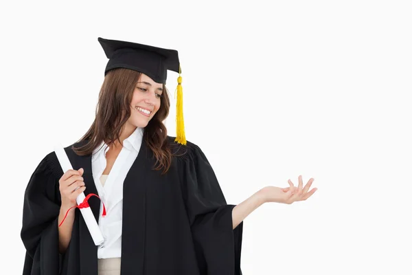 A woman holding her hand out with a degree in her other hand as — Stock Photo, Image