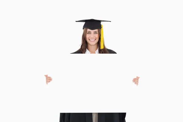 Uma mulher em seu vestido de formatura detém uma folha em branco na frente de h — Fotografia de Stock