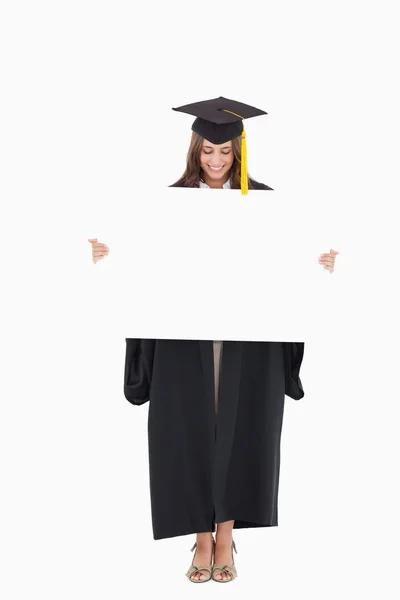 A smiling woman as she holds and looks at a blank sheet in front — Stock Photo, Image