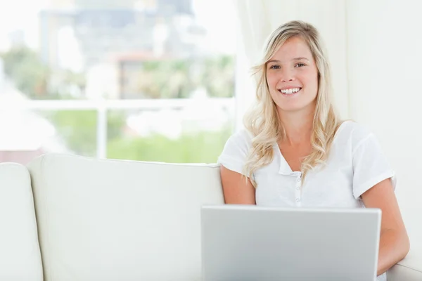 Una mujer sonriente sosteniendo un portátil en sus manos mientras mira —  Fotos de Stock