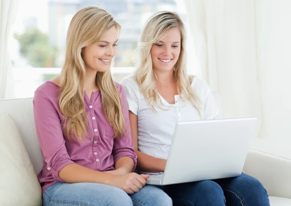 Een meisje en haar vriend op zoek naar een laptop terwijl op de Bank — Stockfoto