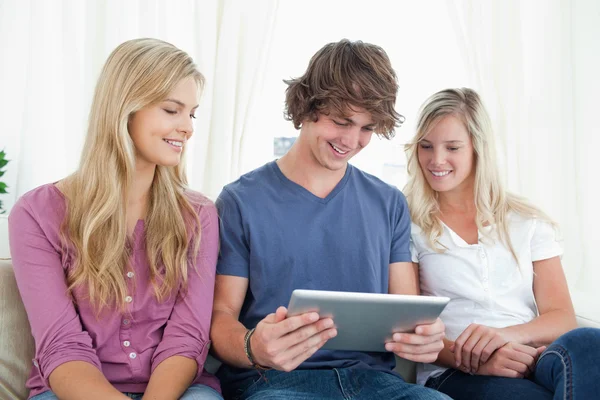 Three friends sit together as they look at a tablet pc — Stock Photo, Image