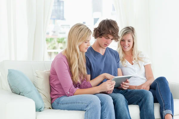 Borther and sisters sit on the couch while looking at a tablet p — Stock Photo, Image