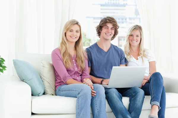 Smiling on the couch as they use the laptop — Stock Photo, Image