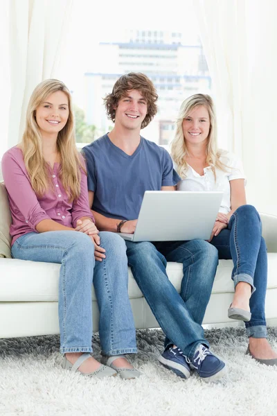 A group of friends sitting together as they use a laptop — Stock Photo, Image