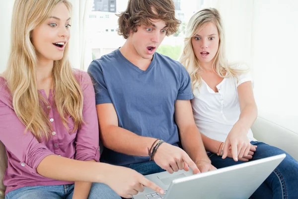 Três amigos chocados com o que está na tela do laptop — Fotografia de Stock