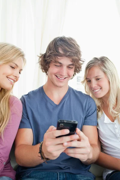 Mann zeigt den beiden Mädchen, was auf seinem Handy ist — Stockfoto