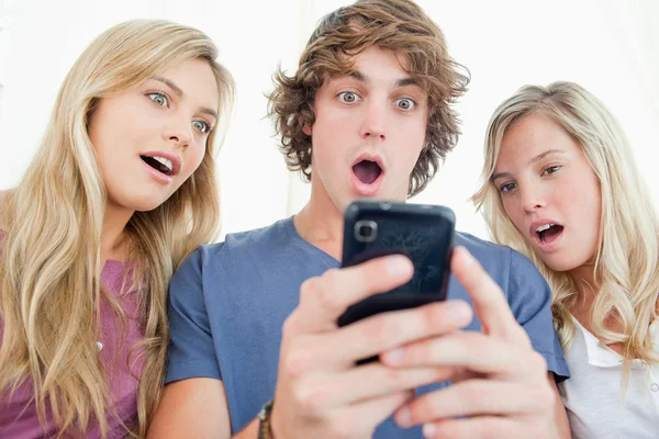 Drei Freunde sind überrascht von der Nachricht am Telefon — Stockfoto