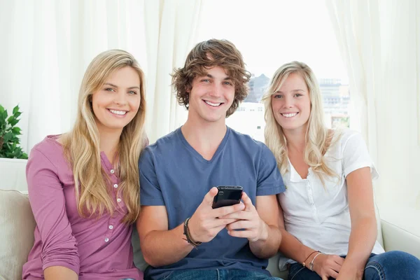 Drie vrienden zitten samen kijken naar de camera — Stockfoto