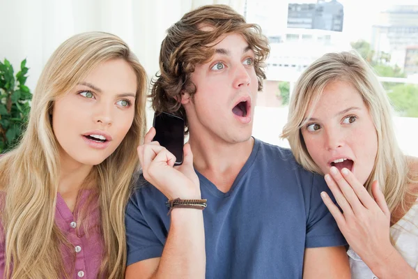 Трое шокированных друзей слушают телефонный разговор — стоковое фото
