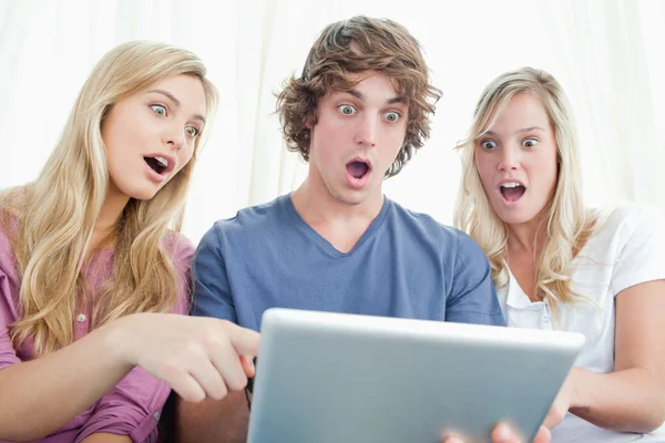 Drei schockierte Freunde blicken auf den Bildschirm des Tablets — Stockfoto