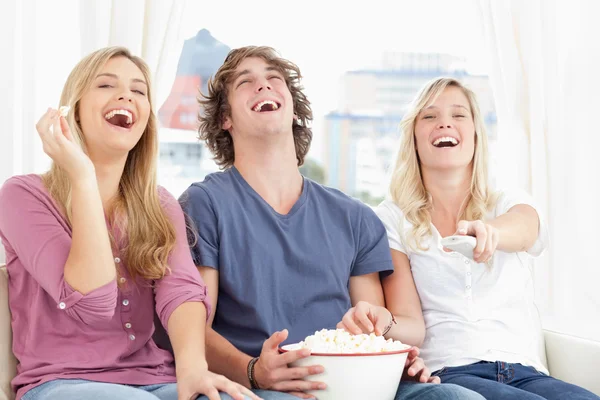 Három barát, étkezési pattogatott kukorica, míg nevetve a show — Stock Fotó