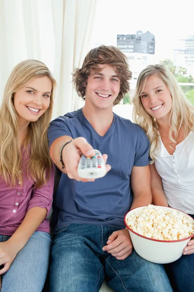 Trzech przyjaciół razem jedzenie popcornu, jak patrzą na aparat — Zdjęcie stockowe