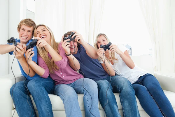 Amigos disfrutando de los videojuegos mientras todos se inclinan hacia un lado —  Fotos de Stock