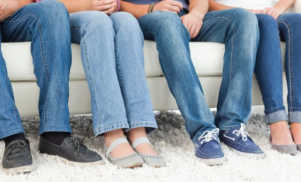 Cztery pary stóp obok siebie przed kanapie — Zdjęcie stockowe