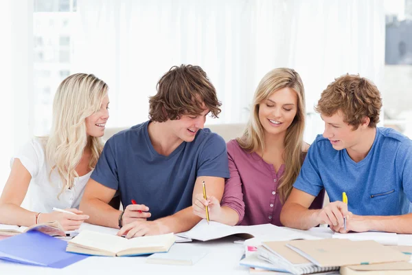 Vier studenten lachen als ze samen werken — Stockfoto