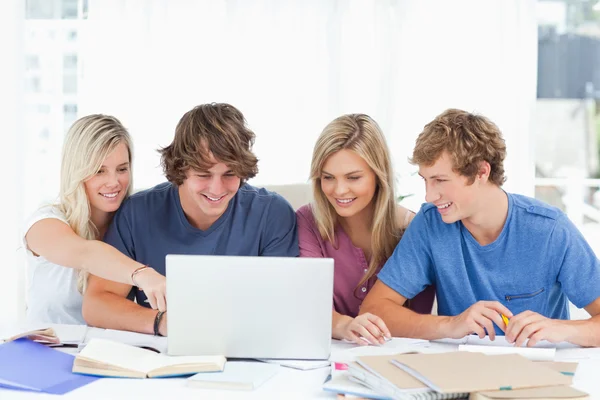 A female student points to the screen as the group use the lapto — Stock Photo, Image