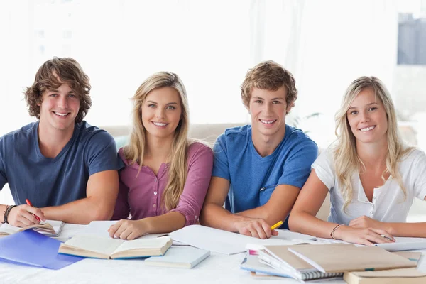 En leende grupp av student sitter och tittar på kameran — Stockfoto