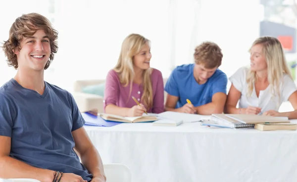 Smiling man sitting on front of his friends and looking at the c — Stock Photo, Image