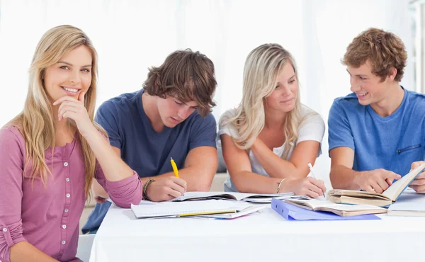 A study group working hard as one girl smiles and looks at the c — Stock Photo, Image