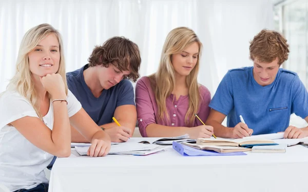 Een studiegroep hard werken als een meisje glimlacht en kijkt naar de c — Stockfoto