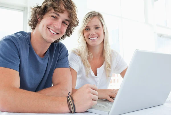 A smiling couple with a laptop looking at the camera — Stock Photo, Image