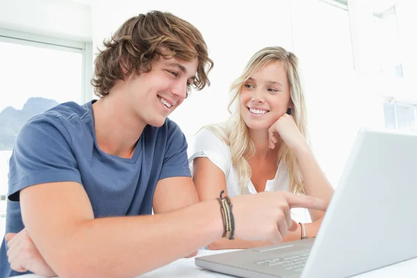 Улыбающаяся пара смотрит на ноутбук с женщиной, смотрящей на — стоковое фото