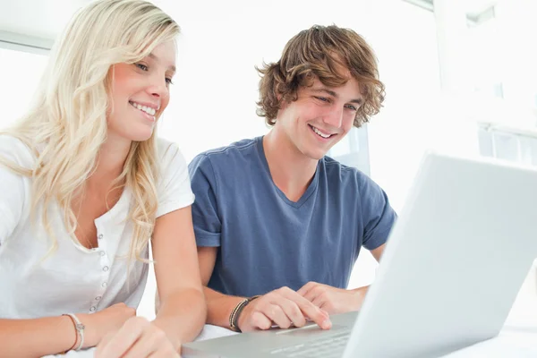 Um casal sorrindo olhando para o laptop juntos — Fotografia de Stock