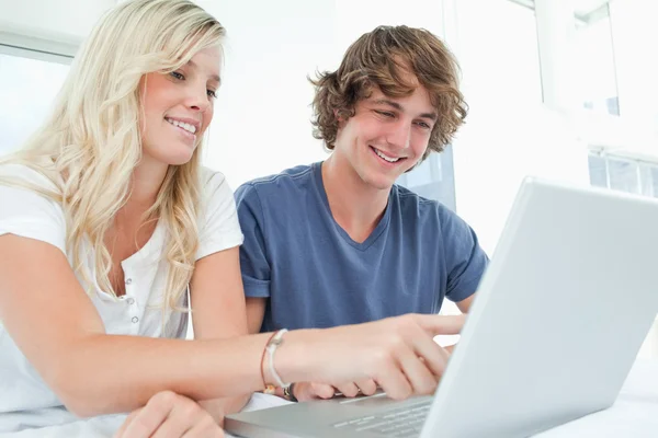 Una coppia sorridente che usa un computer portatile mentre punta lo schermo — Foto Stock