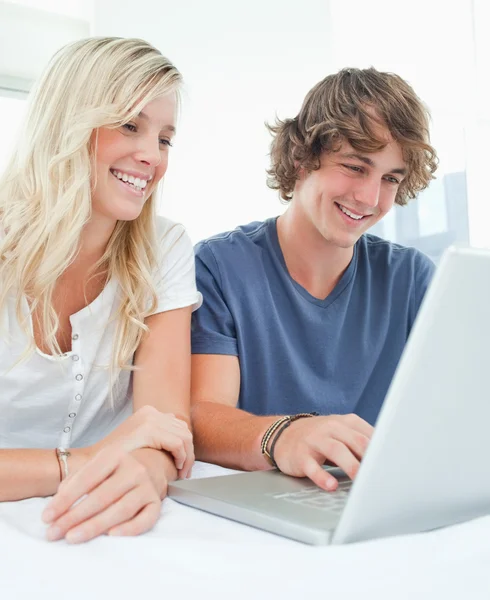 Um casal sorridente se senta junto enquanto navega na internet — Fotografia de Stock