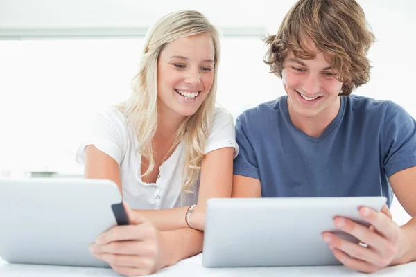 A smiling girl looks into her boyfriends tablet — Stock Photo, Image