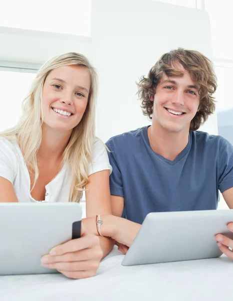 Um casal com tablets sorrir e olhar para a câmera — Fotografia de Stock