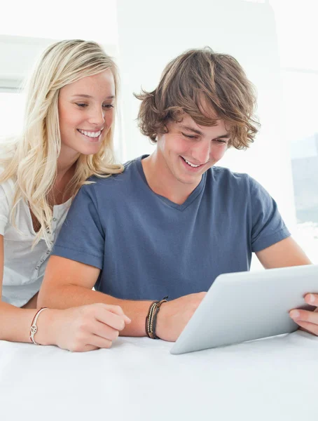 Um casal sorrindo como eles usam um tablet — Fotografia de Stock