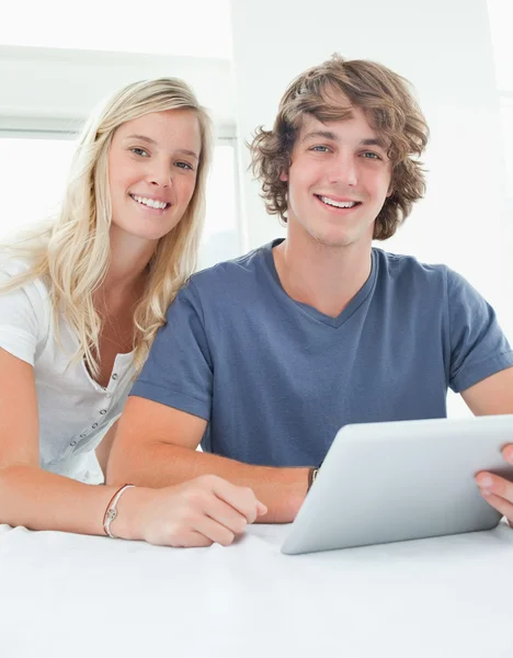Close up smiling couple holding a tablet and looking at the came — Stock Photo, Image