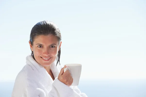 Usmívající se žena v županu s šálkem kávy — Stock fotografie