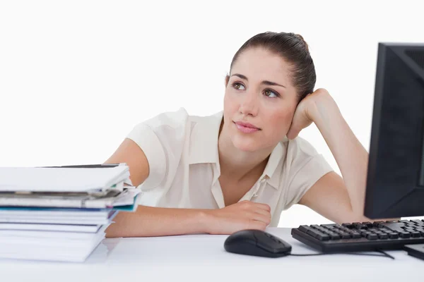 Dreaming businesswoman leaning on her desk — Stock Photo, Image