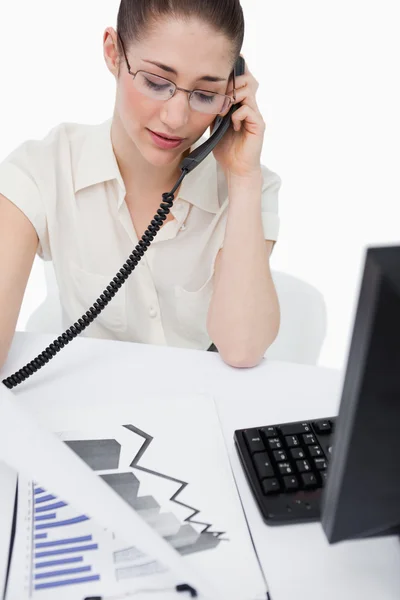 Porträtt av en sekreterare att göra ett telefonsamtal medan du tittar på sta — Stockfoto