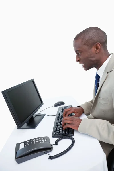 Kızgın bir işadamı bir bilgisayar kullanarak yan görünüm — Stok fotoğraf