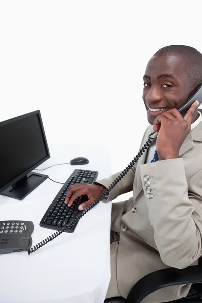 Zijaanzicht van een mannelijke secretaris beantwoorden de telefoon tijdens het gebruik van een — Stockfoto
