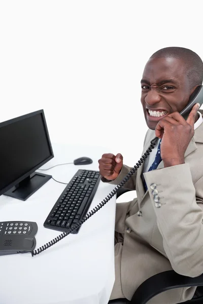 Vista lateral de un hombre de negocios contestando el teléfono mientras usa un mon —  Fotos de Stock