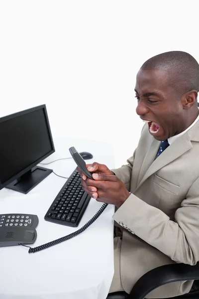 Portrait of an angry businessman answering the phone while using — Stock Photo, Image