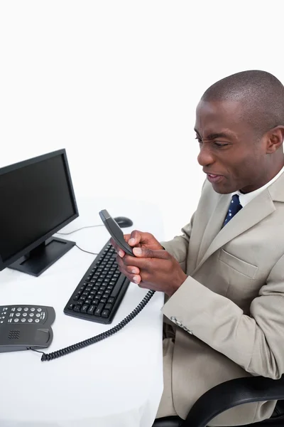 Portrait of an angry businessman talking to the phone while usin — Stock Photo, Image