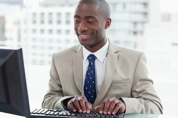 Bir bilgisayarı kullanarak gülümseyen ofis çalışanı — Stok fotoğraf